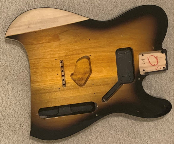 Two color burst Squire guitar body with a cutout taken from the back and an arm carve